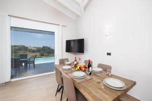 a dining room with a table and chairs and a large window at Casa di Pietra in Lakíthra