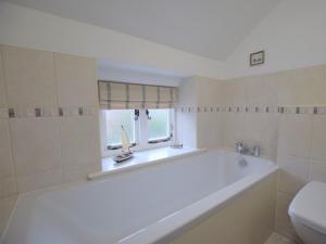 Una bañera blanca en un baño con ventana. en 3 bed in Southrepps 76795, en Northrepps 15 fotos más
