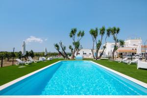 a pool with chaise lounge chairs and palm trees at Quinta Alegre Tavira T3 in Luz de Tavira