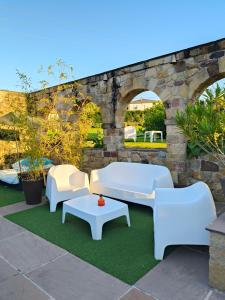 a patio with four white couches and a table at Apartamentos la Leyenda in Santillana del Mar +29 photos