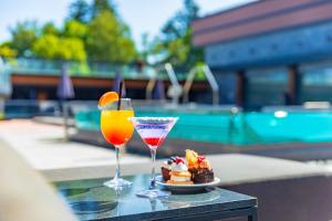 two cocktails and desserts on a table next to a pool at Grand Hotel Bansko - Fitness & SPA in Bansko
