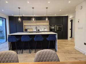 a kitchen with a large island with blue bar stools at Sunset Gable in Gawcott