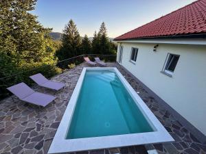 a swimming pool with two chairs and a house at Villa Pika in Delnice
