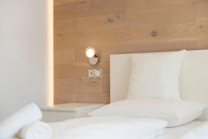 Un dormitorio con una cama blanca con cabecero de madera. en Apt Hofer Elisabeth, en Villabassa