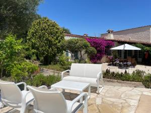 - un ensemble de chaises blanches et d'une table sur une terrasse dans l'établissement Domaine des Tuilières avec piscine, à Vallauris