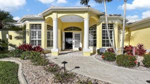 a yellow house with a porch and a driveway at Rosegarden - PoolSpa and perfect water view in Cape Coral