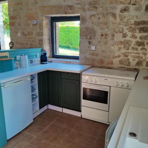 una cocina con armarios verdes y una estufa blanca en Les Écuries, 
