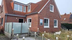 una casa de ladrillo rojo con una valla delante de ella en Ferienwohung Lüttje Eiland, en Norderney