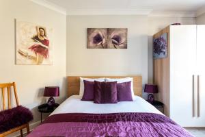 a bedroom with a purple bed and two paintings at Ultra Luxury London w Kensington balcony condo in London