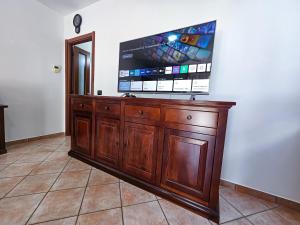 a wooden entertainment center with a flat screen tv on a wall at Malpensa Retreat in Ferno