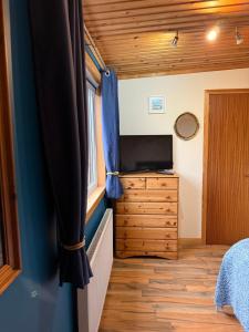 a bedroom with a tv and a dresser in a tiny house at Sea View B & B in Ulsta