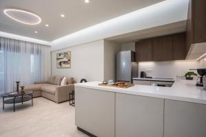 a kitchen with white cabinets and a living room at Vasi Luxury Apartment in Rhodes Town