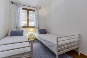 Dos camas en una habitación con ventana. en Indaco Blu, en SantʼAnna Arresi