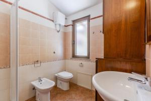 Un baño con inodoro, lavabo y espejo. en Indaco Blu, en SantʼAnna Arresi 14 fotos más