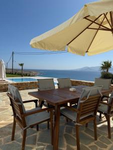una mesa de madera y sillas con sombrilla en Galazio, en Naxos Chora
