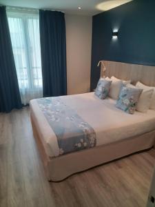 a bedroom with a large bed with blue curtains at Hotel Modern Est in Paris