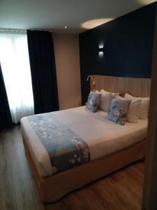 a bedroom with a large bed with blue pillows at Hotel Modern Est in Paris