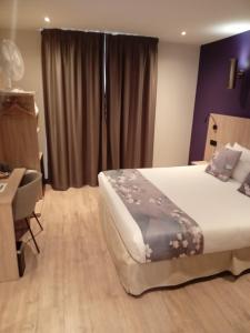 a bedroom with a bed and a desk and a window at Hotel Modern Est in Paris