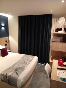 a bedroom with a bed and a black curtain at Hotel Modern Est in Paris