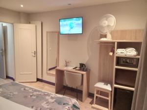 a bedroom with a bed and a desk and a tv on the wall at Hotel Modern Est in Paris