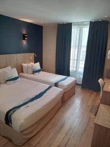 two beds in a hotel room with blue curtains at Hotel Modern Est in Paris
