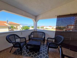 a porch with four chairs and a table and a window at Apartments Rosa Soldatica in Vir