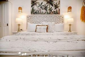 a white bedroom with a large white bed with two lamps at Chic Couples Retreat in Port Douglas +15 photos