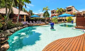 a swimming pool with chairs and umbrellas at a resort at Chic Couples Retreat in Port Douglas