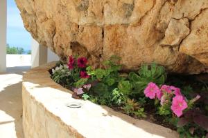 a planter with flowers in front of a stone wall at Appartamenti da Clarissa in Macari