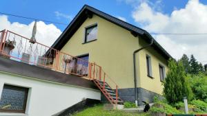 une maison jaune avec un balcon rouge dans l'établissement Ferienhaus Riedl, à Klingenthal