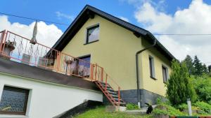 a yellow house with a red balcony at Ferienhaus Riedl in Klingenthal