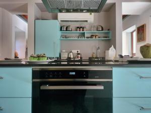 a kitchen with a black oven and blue cabinets at Baron's Antiquarian Villa in Cochin +6 photos