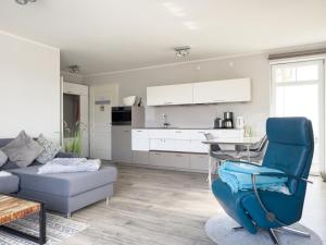 a living room with a blue chair and a kitchen at Ferienwohnung Baltic Lounge 53 in Haffkrug