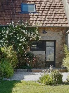 a house with a window and a bush with white flowers at La Dunette, un nid douillet entre mer et campagne in Carolles