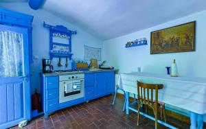 a blue kitchen with a stove and a table at La Lipoveni in Jurilovca