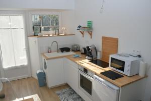 a small kitchen with a microwave and a stove at La Dunette, un nid douillet entre mer et campagne in Carolles +17 photos