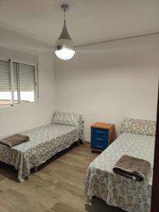 Una habitación con dos camas y una mesa y una ventana. en Avenida Mediterráneo, en Puerto Sagunto