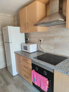Una cocina con estufa y refrigerador blanco. en Avenida Mediterráneo, en Puerto Sagunto
