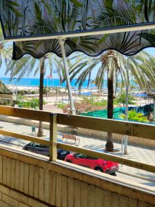 Un coche rojo circulando por una carretera con palmeras. en Avenida Mediterráneo, en Puerto Sagunto 12 fotos más