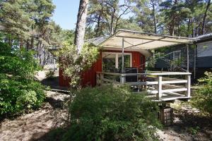 a red cabin in the woods with a porch at Ferienhaus Tipi 365 - strandnahes Ferienhäuschen mit Terrasse und kostenfreier Nutzung des AHOI!-Schwimmbades in Sellin in Göhren