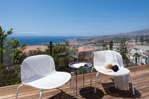 2 Stühle und ein Tisch auf einer Terrasse mit Aussicht in der Unterkunft Karat Villa Stone in Adeje