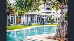 马库拉Rooftop Apartment - Heated Pool & Beach access的建筑物前有棕榈树的游泳池