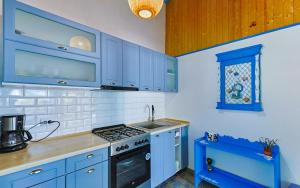 a kitchen with blue cabinets and a stove top oven at Casa EMMA in Jurilovca
