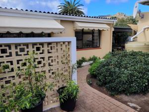 a fence in front of a house with plants at Cowes Cottage in Fish hoek