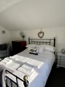 - un lit blanc avec des draps blancs et des serviettes dans l'établissement The Garret Studio Apartment,Balcony views & Parking, à Topsham