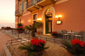 un bâtiment avec des tables, des chaises et des fleurs rouges dans l'établissement Hotel Residence Baiadelsole, à Laigueglia