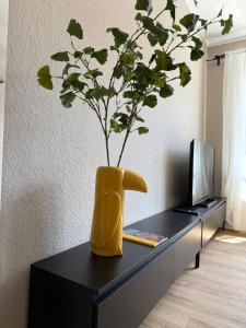eine gelbe Vase mit einer Pflanze darin auf einem Schreibtisch in der Unterkunft Apartment 1 Urban Vibe in Hannover