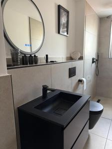 ein Badezimmer mit einem schwarzen Waschbecken und einem Spiegel in der Unterkunft Apartment 1 Urban Vibe in Hannover + 9 Fotos
