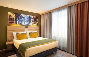 a bedroom with a large bed with yellow pillows at Leonardo Boutique Hotel Salzburg Gablerbräu in Salzburg