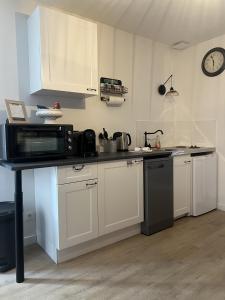 a kitchen with white cabinets and a black microwave at L’Etape, cœur de ville in La Charité-sur-Loire